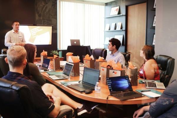 man standing in front of people sitting beside table with laptop computers, IT Company