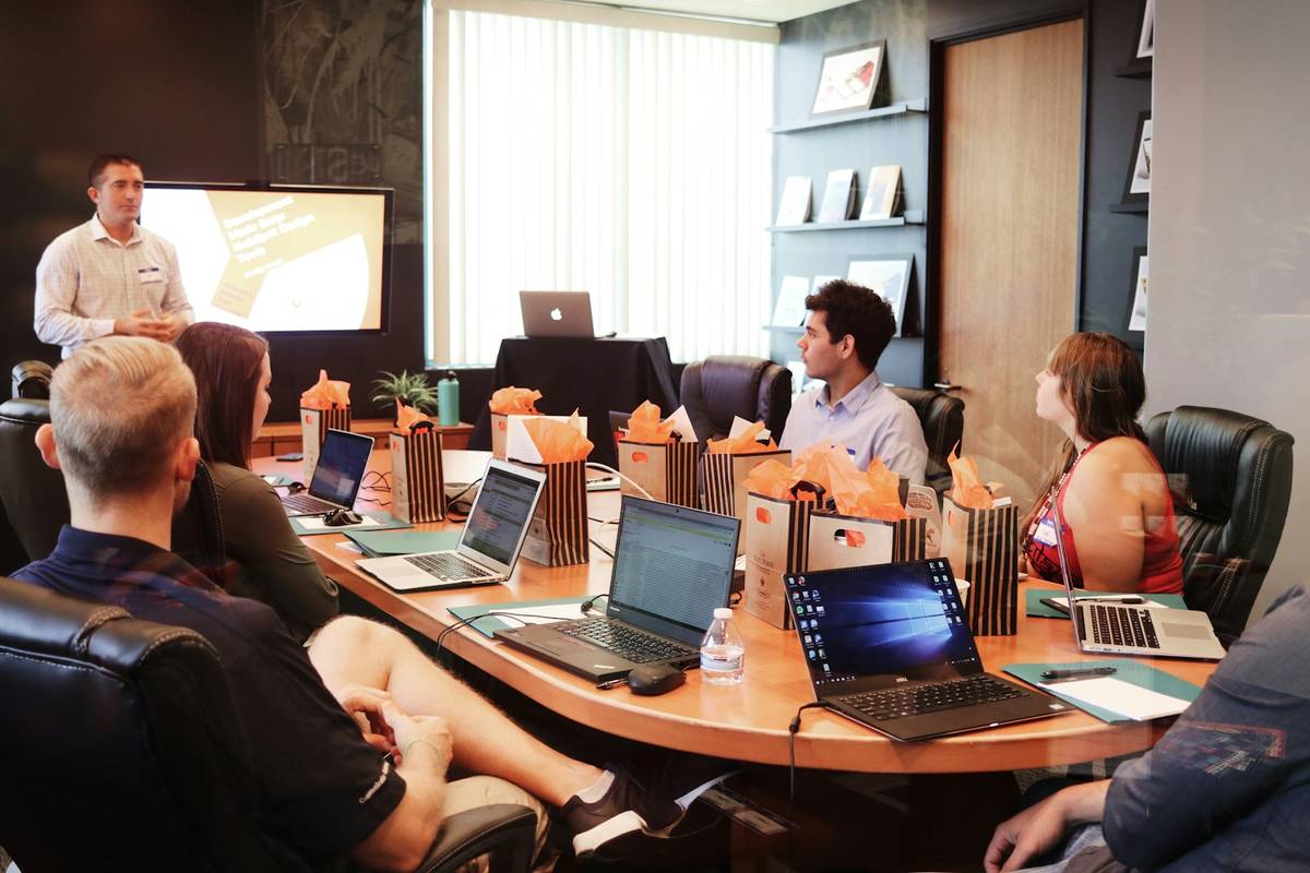 man standing in front of people sitting beside table with laptop computers, IT Company